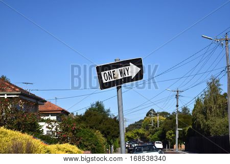one way crooked street sign against suburban street and blue sky