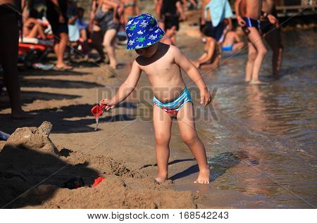 DIDIM TURKEY - JULY 9 2014. Baby boy playing with toys on the sea.
