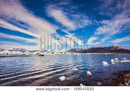 The ice floes and cirrocumulus clouds of lagoon Jokulsarlon, Iceland. Clouds reflected in the water of lagoon. The concept of northern extreme tourism