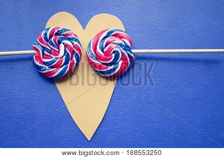 andy swirl rainbow round two lollipops on heart-shaped. Candy stripes on a stick on blue background. Love concept. February 14. Holidays happy valentines day celebration.. Valentine theme.