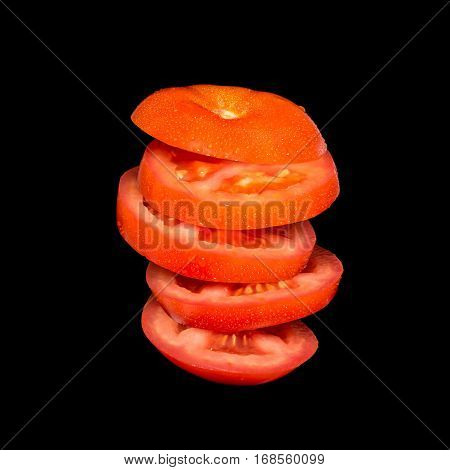 Flying tomato. Sliced red tomato isolated on black background. Levity vegetable floating in the air.