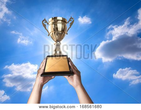 A Man Holding Up A Gold Trophy Cup With Bluse Sky And Sun Background Copy Space Ready For Your Troph