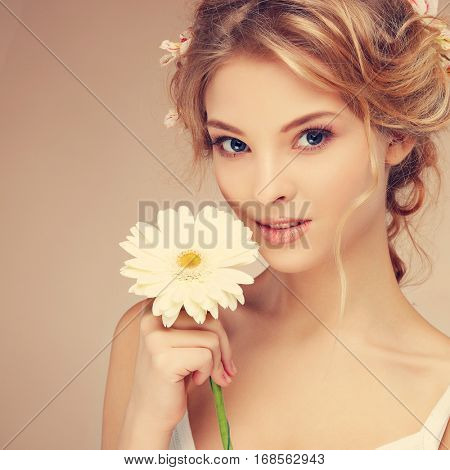 Beautiful girl, isolated on a light - grey background with varicoloured flowers in hairs, emotions, cosmetics