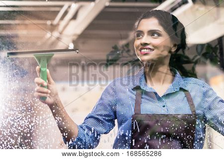 Indian employee cleaning windows with squeegee