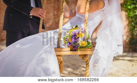 Wedding couple on a swing and bouquet