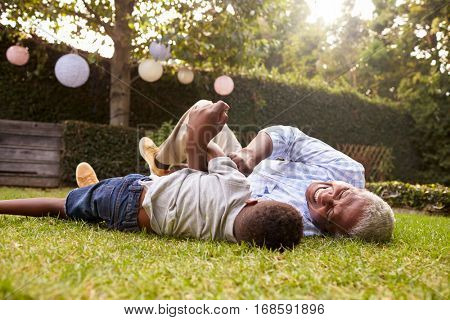 Grandfather and grandson play lying on grass, low angle