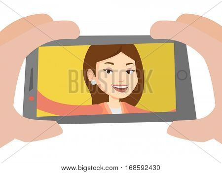 Young joyful caucasian woman making selfie. Smiling woman making selfie with cellphone. Woman taking selfie. Vector flat design illustration isolated on white background.