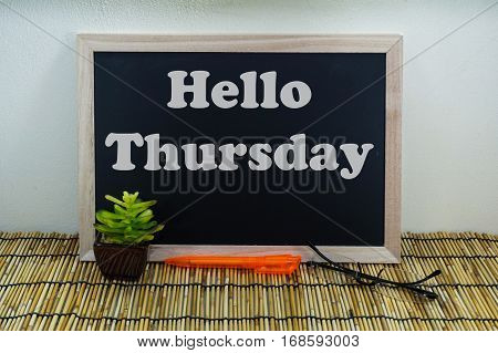 Business & creative concept,Hello Thursday word on blackboard with green plant,pen & spectacle eyeglasses.