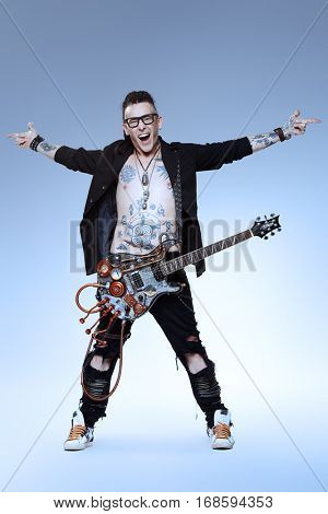 Excited rock musician is playing electrical guitar. Full length studio shot. Entertainment and musical concept. 