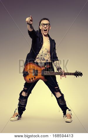 Excited rock musician is playing electrical guitar. Full length studio shot. Entertainment and musical concept. 