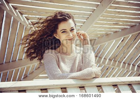 Curly girl smiling with happiness in a sunny alcove close-up
