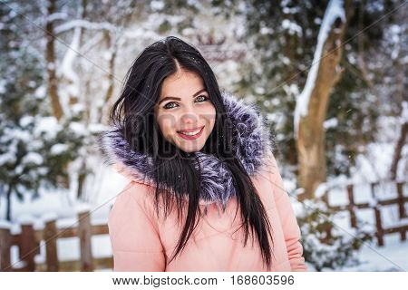 Winter. Girl brunette capless smiles on the background of snow. Close-up