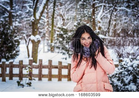 Winter. Girl brunette capless smiles on the background of snow. Close-up