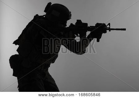 United states Marine Corps special operations command Marsoc raider with weapon aiming a gun. Silhouette of Marine Special Operator gray background