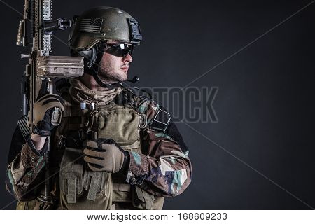 United states Marine Corps special operations command Marsoc raider with weapon. Studio shot of Marine Special Operator half-turning black background
