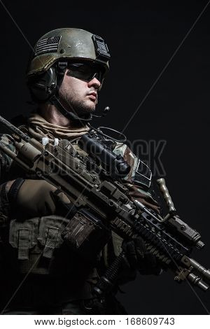 United states Marine Corps special operations command Marsoc raider with weapon. Studio shot of Marine Special Operator half-turning black background