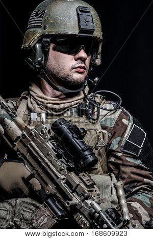 United states Marine Corps special operations command Marsoc raider with weapon. Studio shot of Marine Special Operator half-turning black background