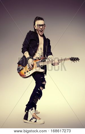 Excited rock musician is playing electrical guitar. Full length studio shot. Entertainment and musical concept. 