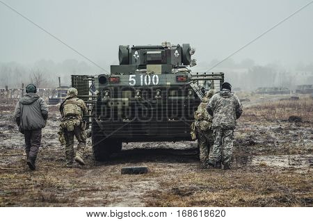 Ukrainian soldiers run after the Armoured personnel carrier (APC) on military training in fog landscape