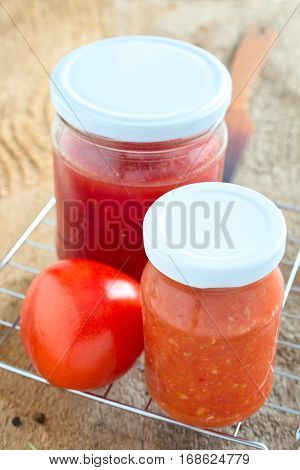 Two glasses of tomato juice and one fresh tomato.