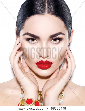 Gorgeous Young Brunette Woman face portrait. Beauty Model Girl with bright eyebrows, perfect make-up, red lips, touching her face. Sexy lady makeup for party. Isolated on white background