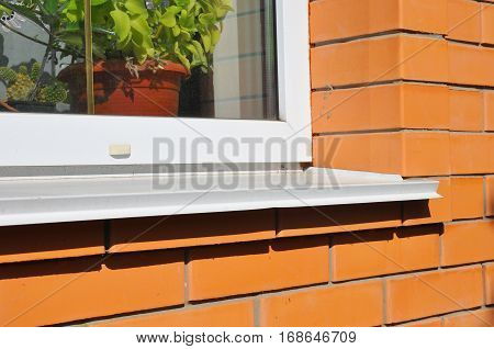 Plastic window with white metal sill. Brick House Wall