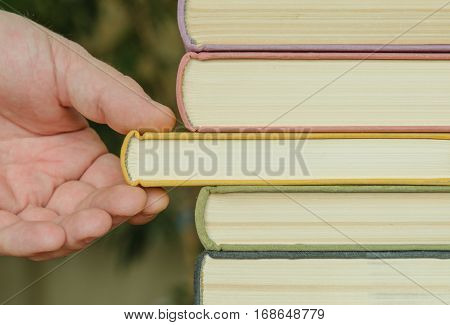 hand of man or woman takes a book on a shalf in the room or library