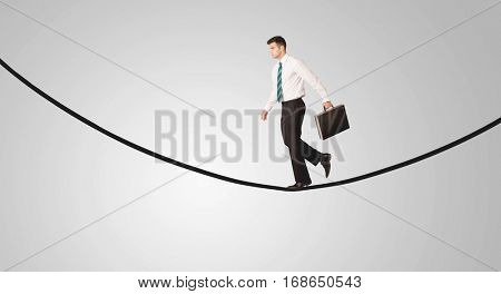 A confident smiling salesman balancing on black wire in clear grey empty space concept