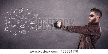 An elegant hipster guy trying to use a vintage camera with camera settings icons drawn on wall, like flash, white balace or ISO value concept