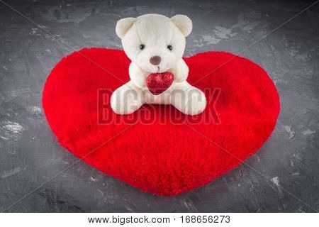 White teddy bear with love letter on red heart on gray background. Say i love you for valentine 's day concept.