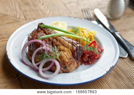 Grilled pork ribs with sauerkraut and mashed potatoes on restaurant table - hearty dish