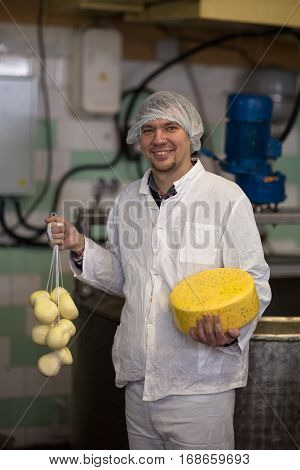 worker on the production of cheese at the dairy small with heads of cheese small business concept and production