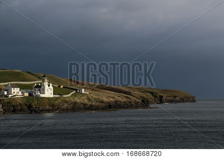 Holburn Head Lighthouse on Thurso Bay, Scrabster, Scotland, UK, dark sea and sky
