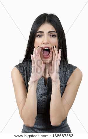 Young business woman wearing a grey dress is using her hands to shout at the camera.
