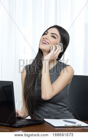 Young business woman talking on the phone and smiling.