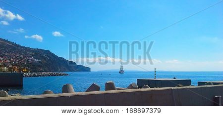 Sailboat in the ocean near the shore with breakwater. Atlantic Ocean Madeira Portugal