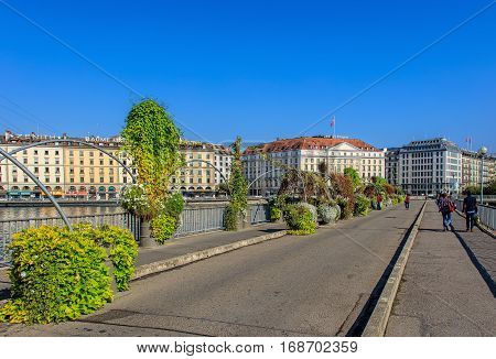 Geneva, Switzerland - 24 September, 2016: people on the Pont des Bergues bridge, buildings along the Rhone river. The city of Geneva is the capital of the Swiss Canton of Geneva, it is the second most populous city in Switzerland.