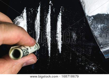 Drug Abuse. Hand of man holds rolled banknote for snorting line of cocaine powder. Problems with drugs concept. Top view.