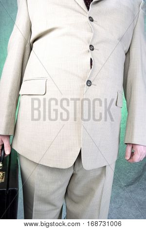 Well-dressed overweight mid-adult man standing and holding briefcase, mid section