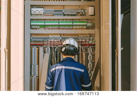Instrument technician on the job check wiring on PLC cabinet