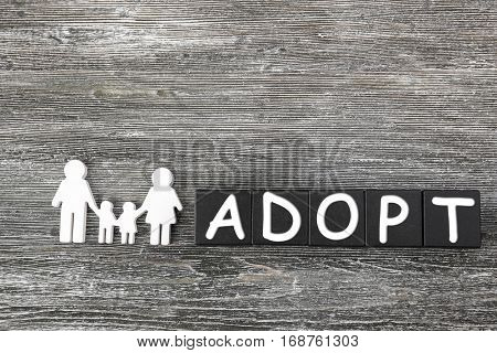 Black cubes with word ADOPT and figure in shape of happy family on wooden background