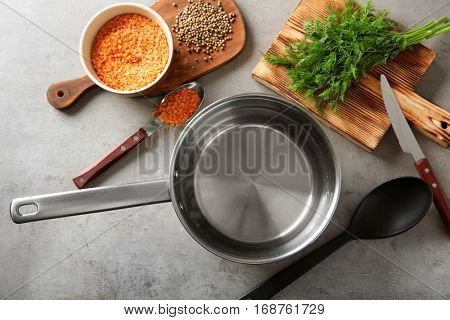 Stainless saucepan, parsley and lentil on grey kitchen table