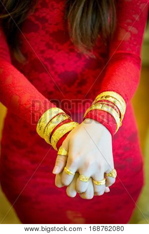 Chinese wedding gold jewelry on wrist and red dress