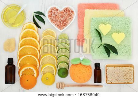 Skin and body care products with citrus fruit, honey, essential and almond oil, himalayan salt and spa accessories on white distressed background. 