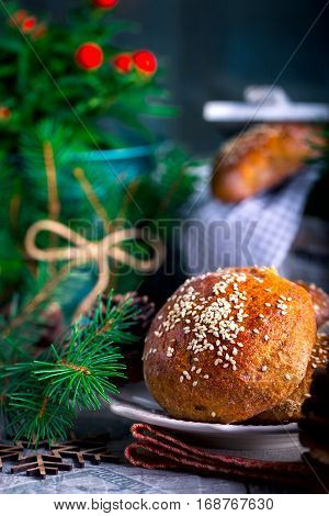 Fresh buns with sesame seeds on a plate. Whole-grain bread. The pine cones. Wooden snowflakes
