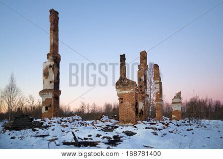 Heating furnaces on the ashes of the burned-down two-storeyed house in the January evening. Working village 