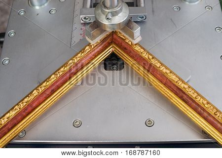 Craftsman working on frame in frameshop. Professional framer hand holding frame angle. Top view.