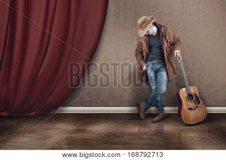 The cowboy with guitar near a curtain.