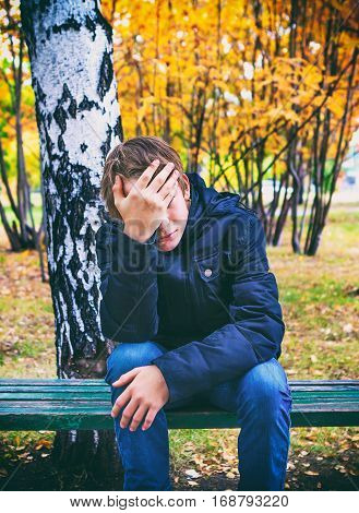 Toned Photo of Stressed Teenager sit on the Bench in the Autumn Park