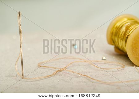 Sewing textile or cloth. Work table of a tailor. Detail of a needle with thread in the workroom reel of thread and natural fabric. . Shallow depth of field. Focus on needle.